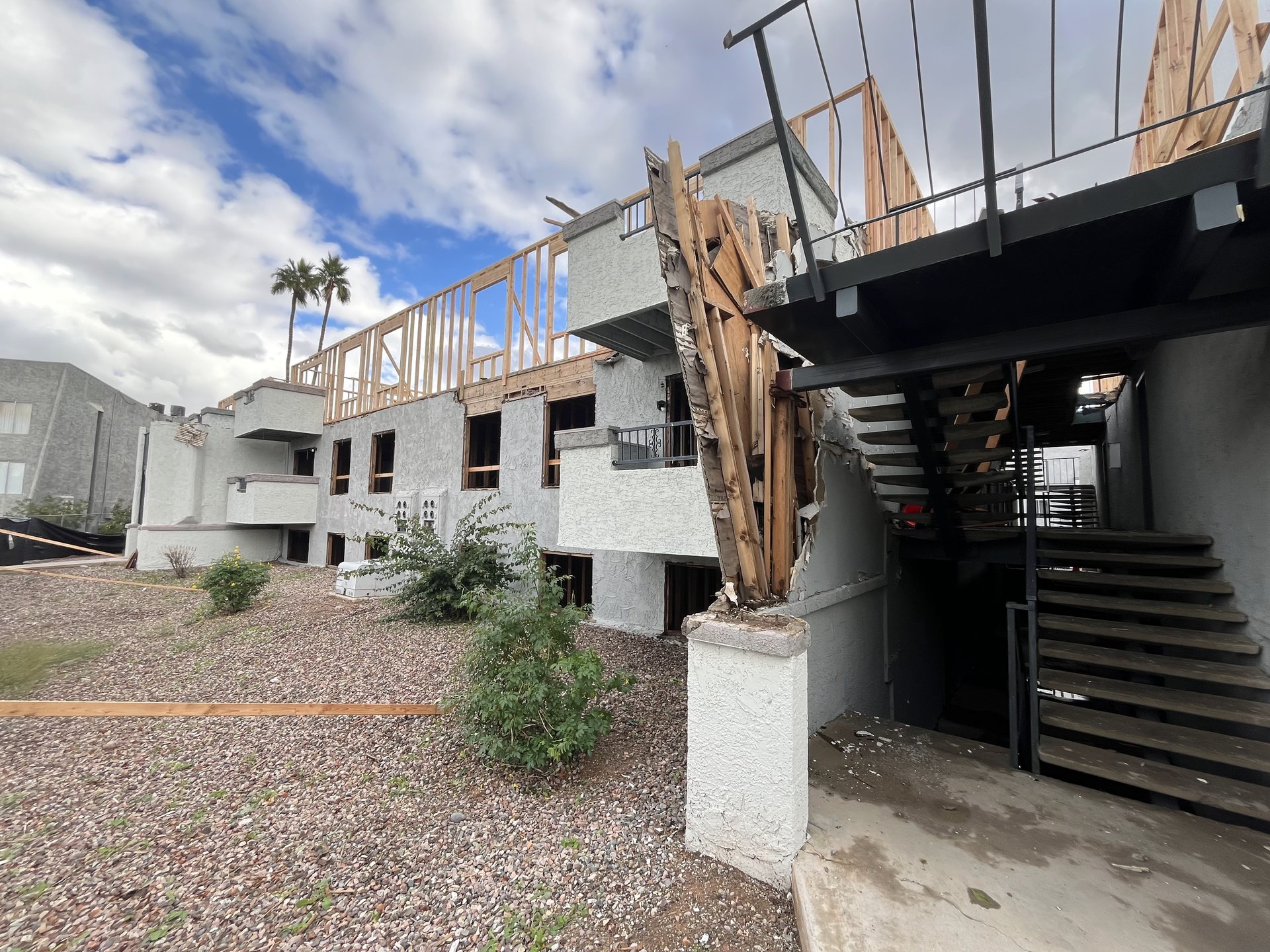 Fire-damaged apartment building in Mesa, AZ with charred framing at the stair tower and a reframed upper floor